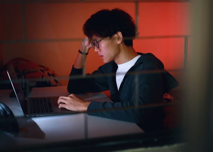 teenage boy reading alone on his laptop late at night